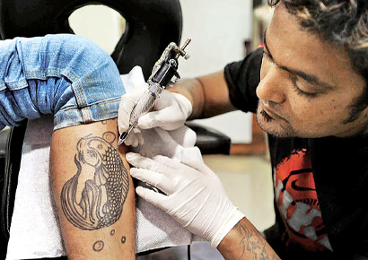 Tattoo artist San creates a new tattoo at his studio in Bandra