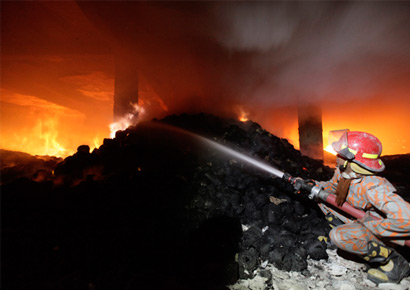 A fireman struggles to bring the fire at a garment factory under control near Dhaka early on Sunday.