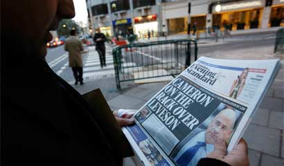 A man reads a newspaper article about Lord Justice Brian Leveson`s report on media practices in central London. British Prime Minister David Cameron said on Thursday that he had serious concerns about legislation to regulate the media, risking a split in his coalition after a damning inquiry triggered by a phone-hacking scandal proposed a press watchdog backed in law.