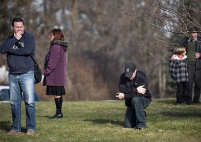 A man kneels as a funeral procession of one of the victims of the Newtown school shooting passes by.