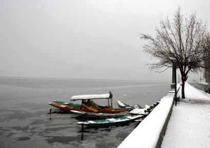 A boatman breaks ice from a a partially frozen Dal lake in Srinagar.