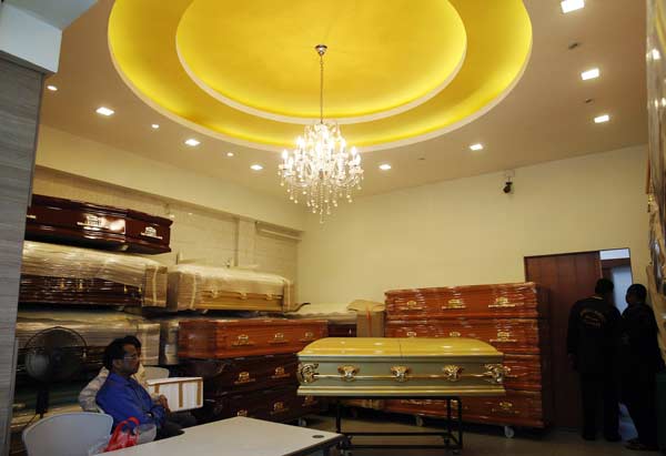 Two Indian High Commission officials (L) sit near the coffin of an Indian rape victim as her body is being embalmed in the next room (R) at a funeral parlour in Singapore.
(Reuters)