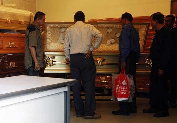 Two Indian High Commission officials (2nd L and 3rd L) inspect the coffin of an Indian rape victim as her body is prepared for embalmment in the next room, at a funeral parlour in Singapore.
(Reuters)