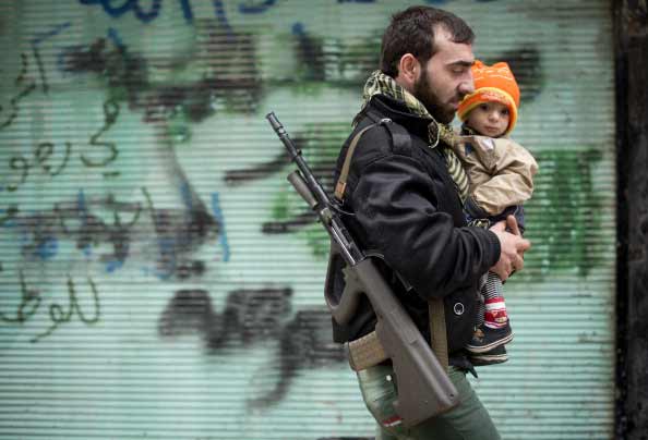 A rebel fighter carries his son after the Friday prayer in the al-Fardos neighbourhood of Aleppo on December 7, 2012.