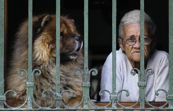 A woman and her dog look out of a window in Havana.
Photo by Desmond Boylan