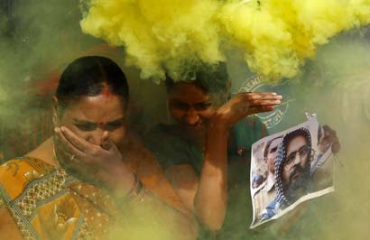 Demonstrators hold a poster of Mohammad Afzal Guru as they take cover from coloured smoke during victory processions that broke out in Ahmedabad hours after his hanging on February 9, 2013.