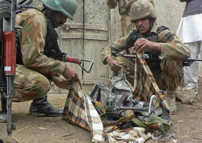 Security officials collect weapons near the site of a police station after it was attacked by militants in Bannu in northwestern Pakistan.