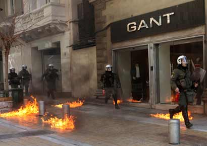 Riot police run by closed shops after protesters threw a petrol bomb following an anti-austerity march during a 24-hour strike in Athens on Wednesday.