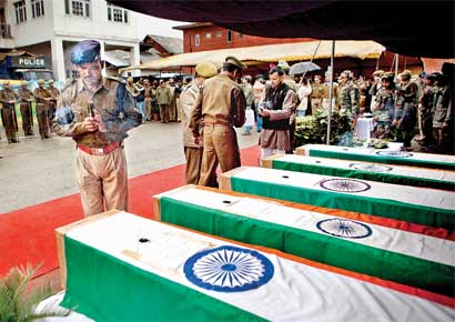 A soldier prays near the coffins of his colleagues at the police headquarters in Srinagar on Wednesday.