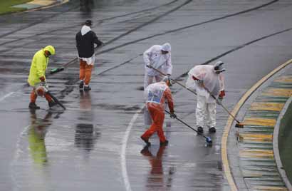Marshals remove excess water on the track before the qualifying session of the Australian F1 Grand Prix at the Albert Park circuit in Melbourne 