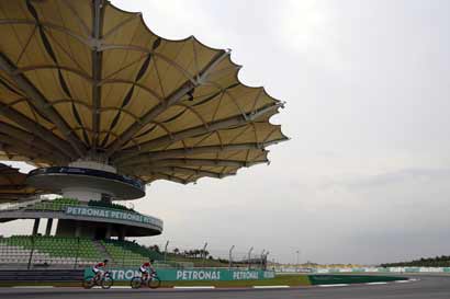 Ferrari driver Fernando Alonso (L) of Spain rides his bicycle around the Sepang International Circuit, ahead of the Malaysia F1 Grand Prix in Sepang
