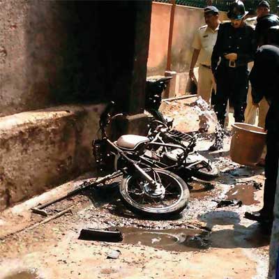 Policemen and fire officials inspect the burnt bike at Bhoiwada police station on Thursday.