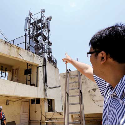 A resident of Dadar's Parsi colony points at a cell phone tower atop a building in the area on Sunday.