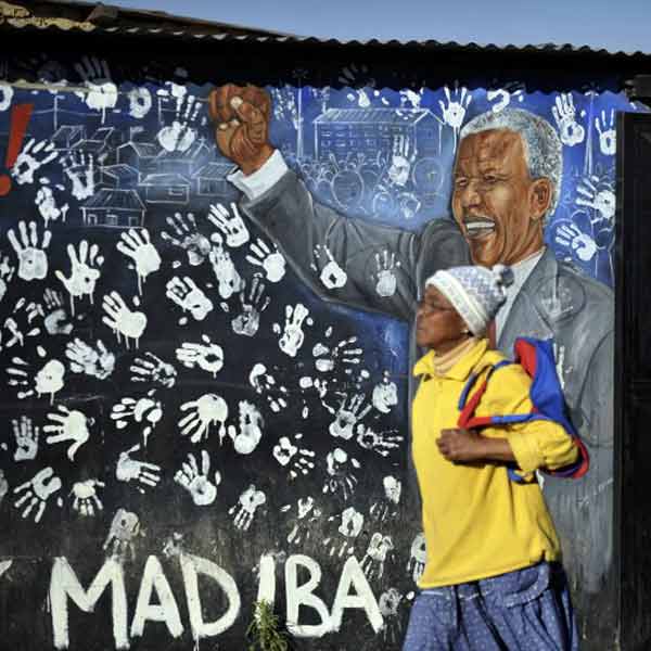 Alexandra's residents walk past a painting of anti-apartheid icon Nelson Mandela in Alexandra near Johannesburg.