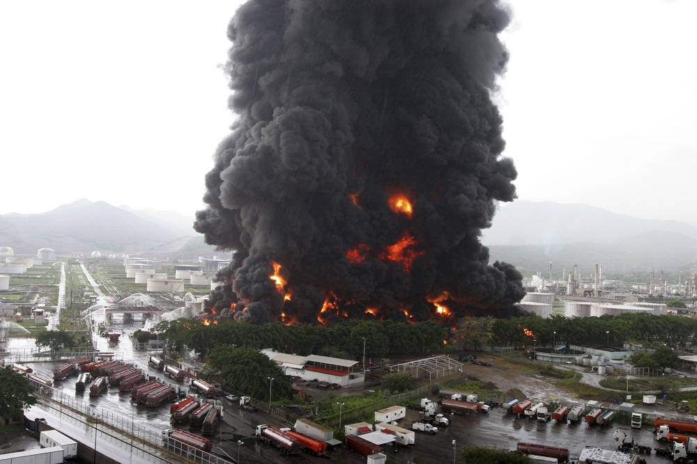 Firefighters try to extinguish a fire at an oil refinery in Puerto La Cruz. Lightning set fire to a storage tank at Venezuela`s Puerto La Cruz oil refinery and residents were moved out of the immediate area.