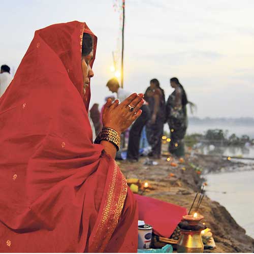 File photo of a woman offering prayers to the rising Sun on the banks of Sabarmati.
