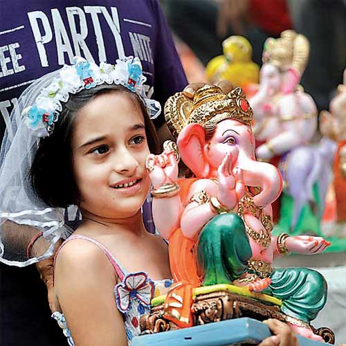 A young girl carries her Ganesha idol home after choosing from an array of colourful idols, on the eve of Ganesha Chaturthi on Sunday.