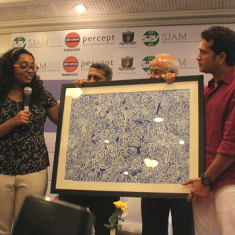 Artist Gayatri Viswanath (left) giving a fleeting explanation of her art after presenting it to Sachin Tendulkar (right). Partly seen behind the work of art are SJAM President Chandrashekar Sant and badminton legend Nandu Natekar. Photo Credit: Abhijit Banare.