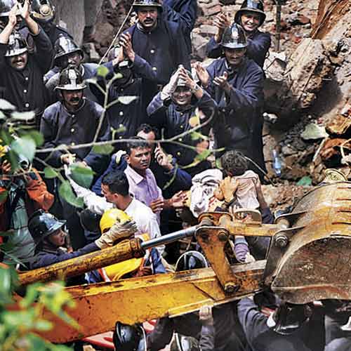 Fire brigade personnel pull out five-year-old Bhagyashree Kamble from under the debris at the building collapse site on Friday. She was trapped for over three hours.