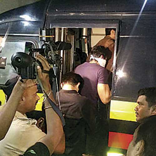The Oshiwara police take some of those detained in the party to a patrol van.