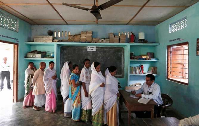 Voters stand in a queue to get their voting slip to cast their vote at a polling station in Majuli, a large river island in the Brahmaputra river, Jorhat district, in the northeastern Indian state of Assam April 7, 2014. The first electors cast their votes in the world's biggest election on Monday with Hindu nationalist opposition candidate Narendra Modi seen holding a strong lead on promises of economic revival and jobs but likely to fall short of a majority. REUTERS/Adnan Abidi (INDIA - Tags: POLITICS ELECTIONS) Voters stand in a queue to get their voting slip to cast their vote at a polling station in Majuli, a large river island in the Brahmaputra river, Jorhat district, in the northeastern Indian state of Assam April 7, 2014. The first electors cast their votes in the world's biggest election on Monday with Hindu nationalist opposition candidate Narendra Modi seen holding a strong lead on promises of economic revival and jobs but likely to fall short of a majority. REUTERS/Adnan Abidi (INDIA - Tags: POLITICS ELE