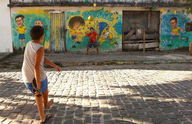 Two boys play soccer in front of caricatures of Brazilian national soccer team players Fred, David Luiz and Neymar (L-R) sprayed on a wall in Porto Seguro June 30, 2014. REUTERS/Arnd Wiegmann Two boys play soccer in front of caricatures of Brazilian national soccer team players Fred, David Luiz and Neymar (L-R) sprayed on a wall in Porto Seguro June 30, 2014. REUTERS/Arnd Wiegmann