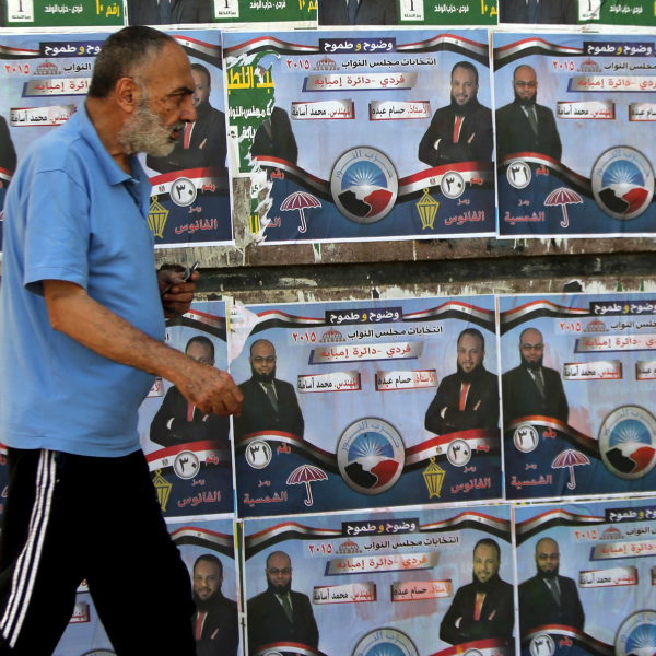 A man walks past election posters for parliamentary candidates of the Nour party Hossam Abdo and Mohammed Osama in the Imbaba di