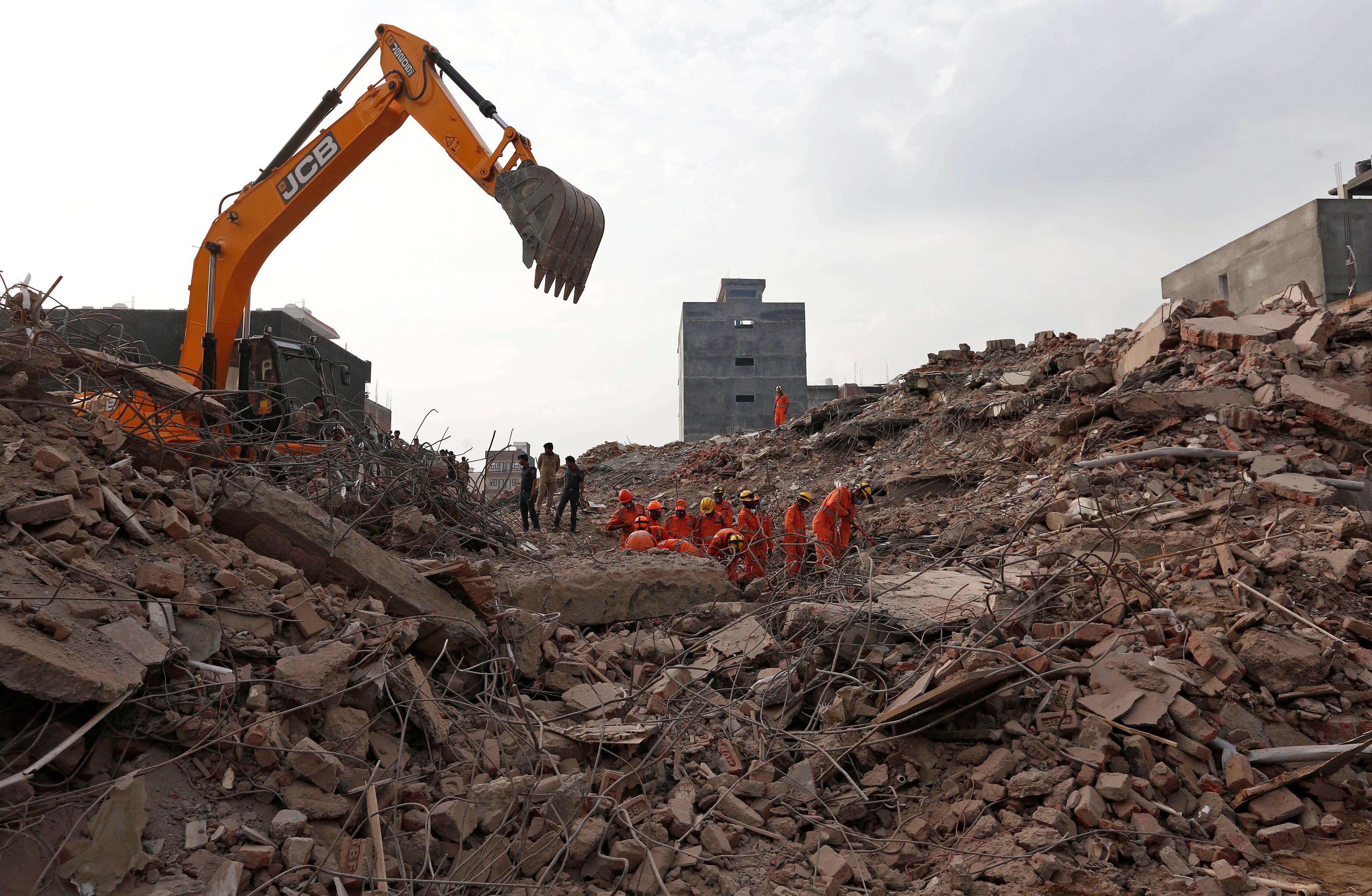 A rescue worker wipes his sweat as he walks back after looking for survivors among the rubbles at the site of a collapsed reside