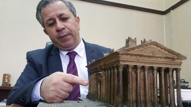 Syria's antiquities chief Maamoun Abdelkarim points at a model of the Bel Temple